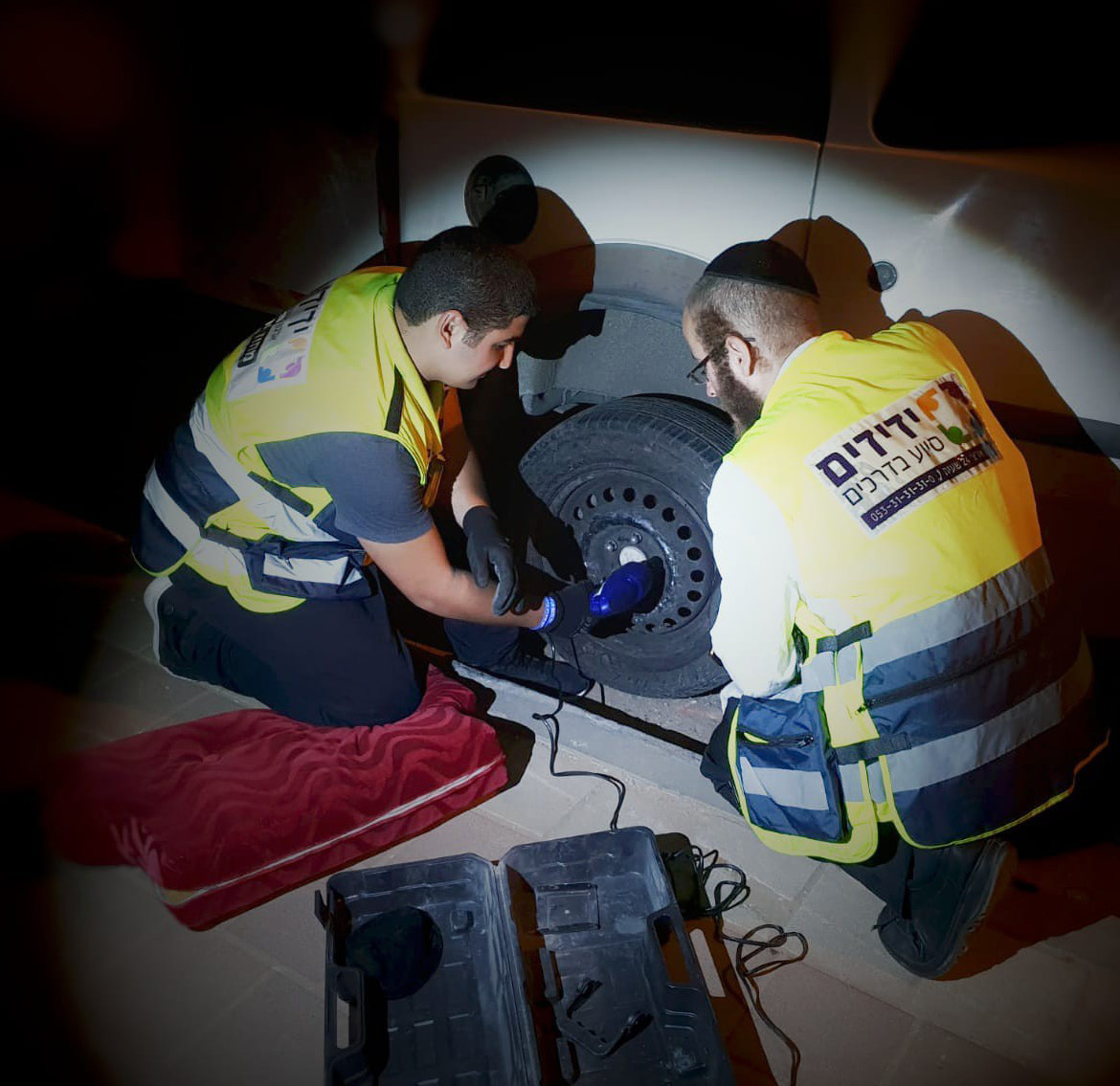 Yedidim volunteers helping change a tire at night